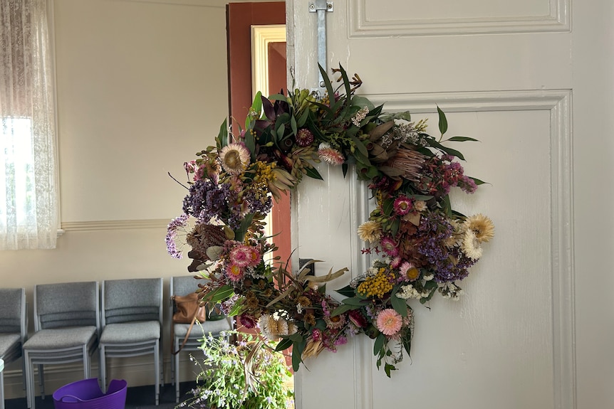 A floral wreath hanging on a white door