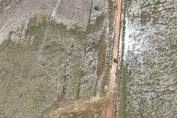 Imagen tomada con un dron de un vehículo que circula por una carretera inundada.
