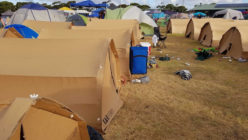 A group of tents made from cardboard, at a music festival.