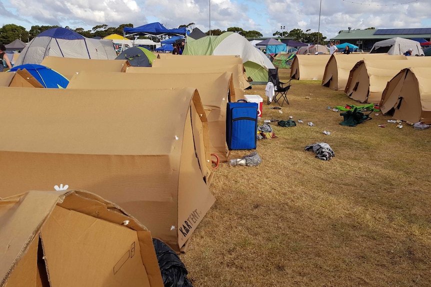 A group of tents made from cardboard, at a music festival.