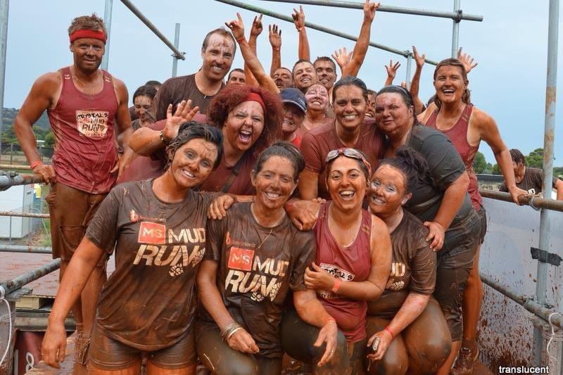 a group of men and women covered in mud from head to toe after completing an obstacle course for charity