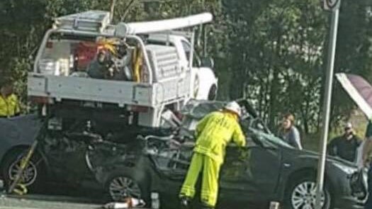 Emergency crews working on ute which landed on cars in Caboolture