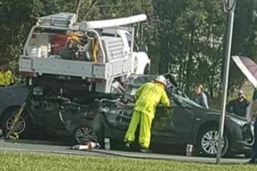 Emergency crews working on ute which landed on cars in Caboolture