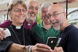 A female Church of England member of clergy takes a selfie with other members of clergy.