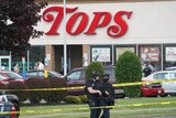 Two armed police stand outside a US supermarket surrounded by police tape