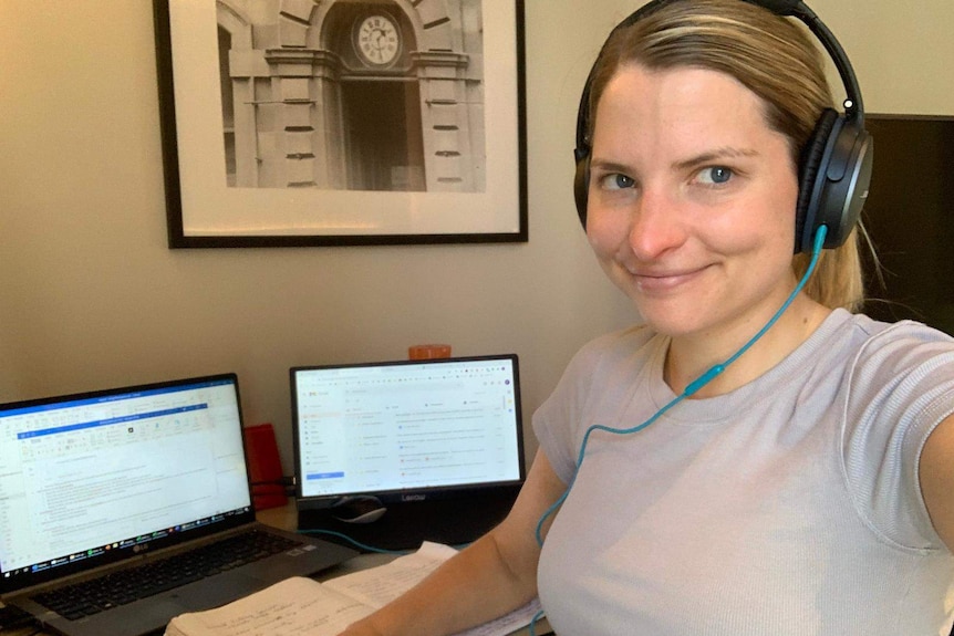 A woman sits at a desk wearing headphones.