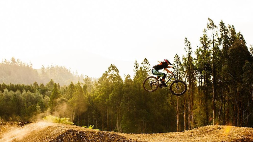 Female rider rides through the air at Maydena Bike Park, Tasmania.
