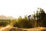 Female rider rides through the air at Maydena Bike Park, Tasmania.