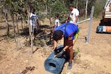A Cairns student unrolling some fencing wire in Cooktown.