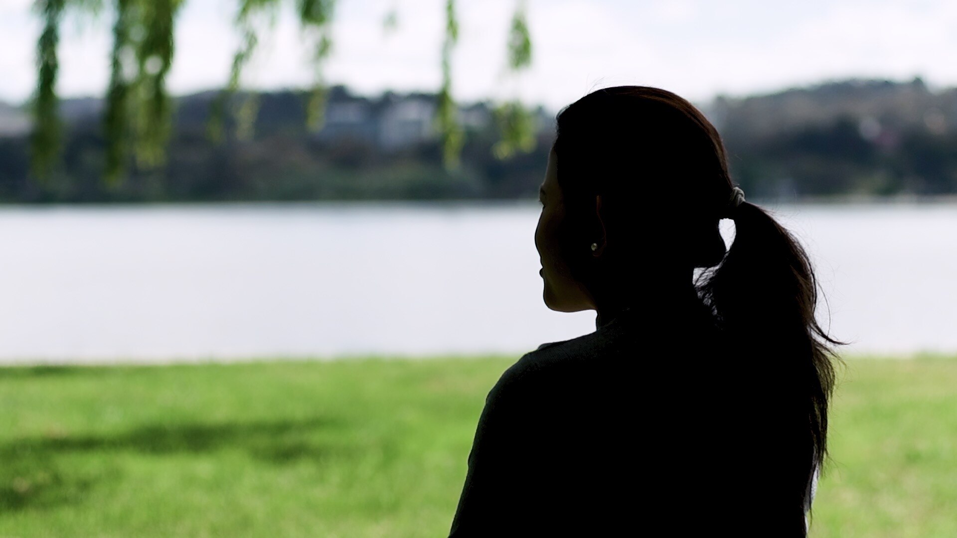 a woman sitting on a park bench with her back to th ecamera