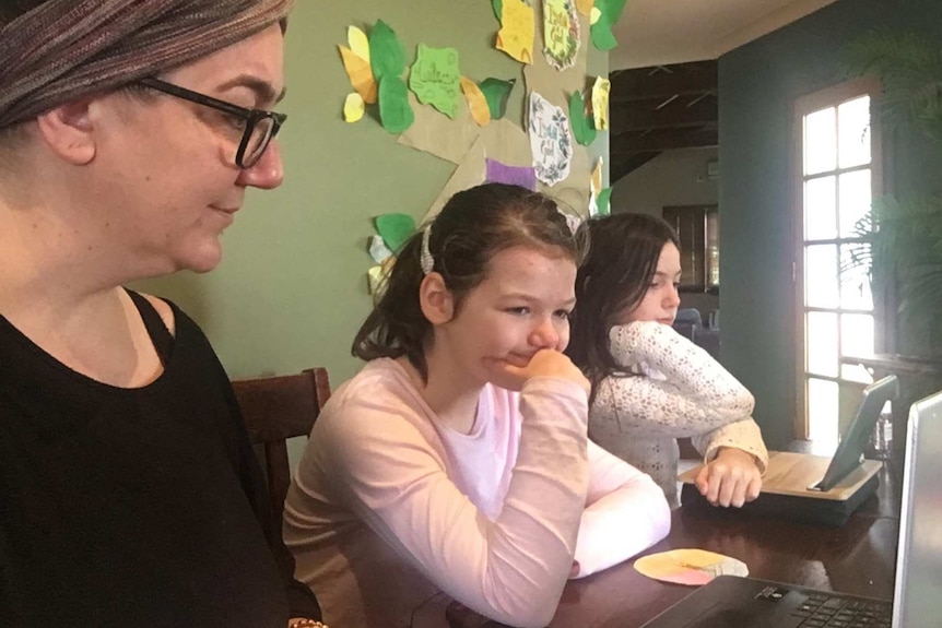 Tasmanian mum Kylie Pearson working with her daughters on laptop computers.