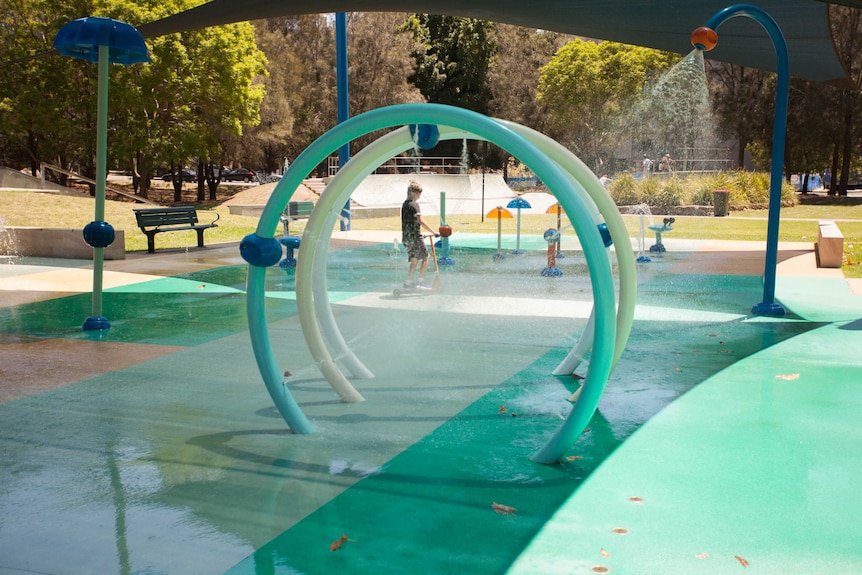 A kid scooters through a water park