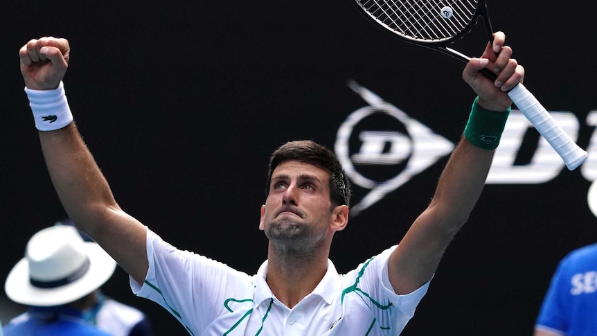 A tennis player spreads his arms wide in triumph after winning an Australian Open match.