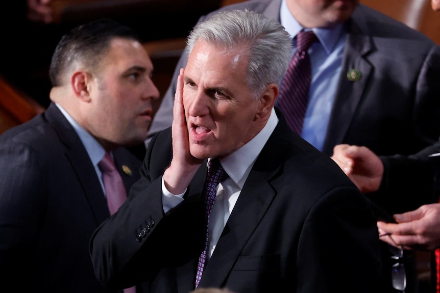 Kevin McCarthy puts his hand up to his face on the floor of the House Chamber.