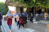 Women wearing headscarves walk out of the front doors of a hotel