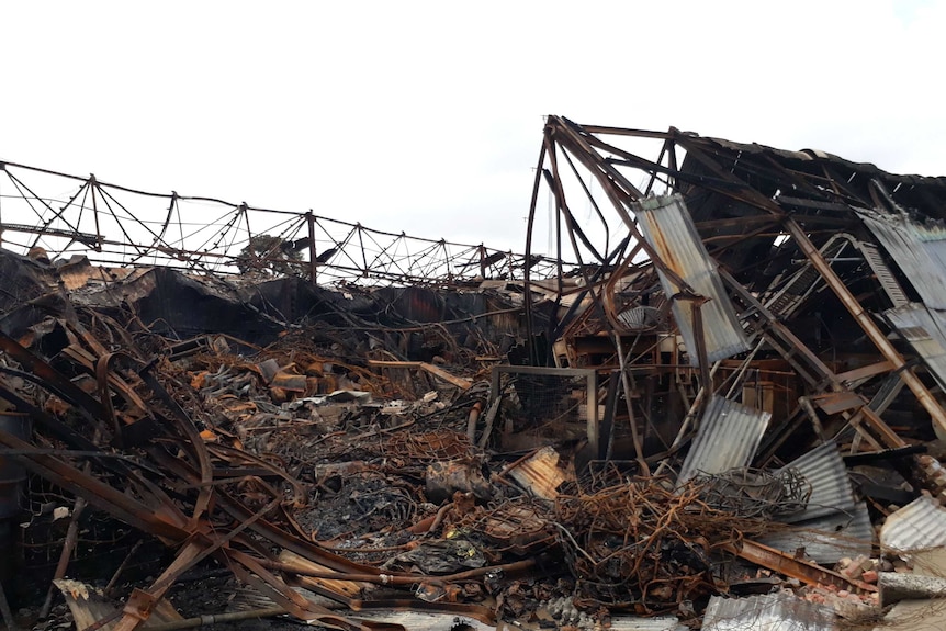 Burnt metal, tin sheets and 44-gallon drums in a warehouse after a fire.