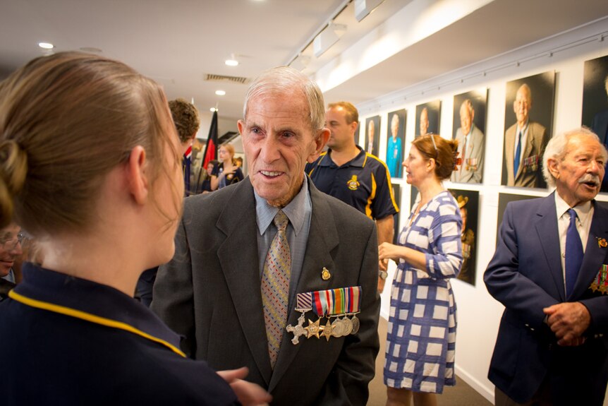 Veteran Howard Hendrick wearing his war medals and talking with a high school student.