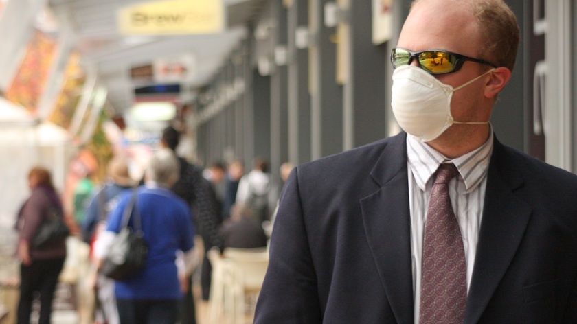A man wearing a swine flu face mask walks down a street