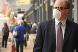 A man wearing a swine flu face mask walks down a street