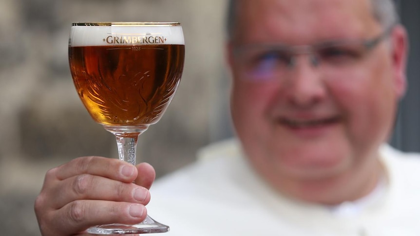 Norbertine monk Father Karel posing with a glass of Grimbergen beer in the foreground.