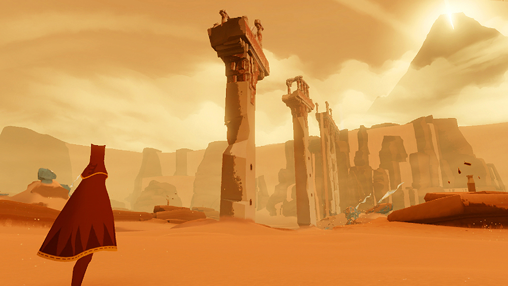 In a scene from a video game a lone caped figure stands in yellow hued desert landscape and looks up at tall ancient ruins.