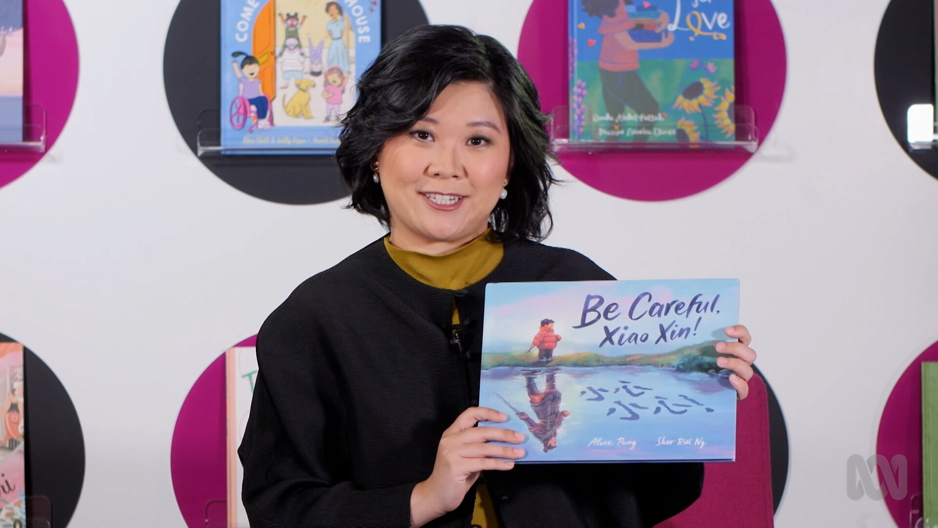 Teacher FangNi Zhou holds up story book, Be Careful, Xiao Xing!