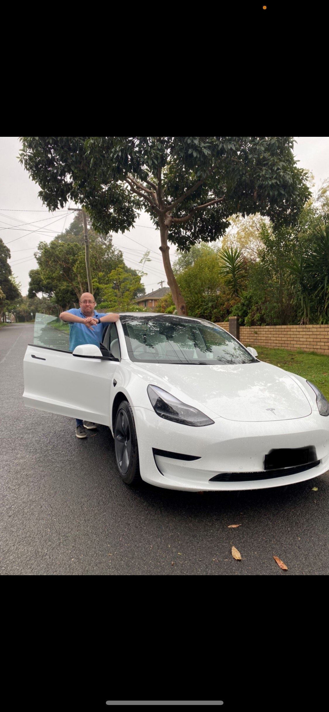 A man smiles while standing next to his car.