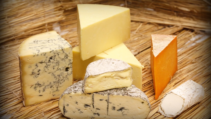 different kinds of cheese are stacked on a timber board