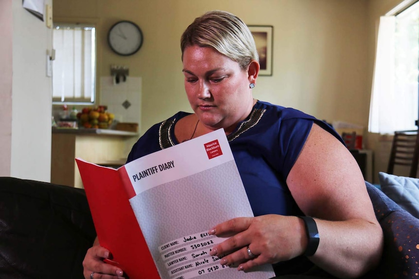 Jodie Elisara looks at legal papers in her house.