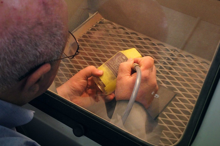 A man sandblasts a label on a glass