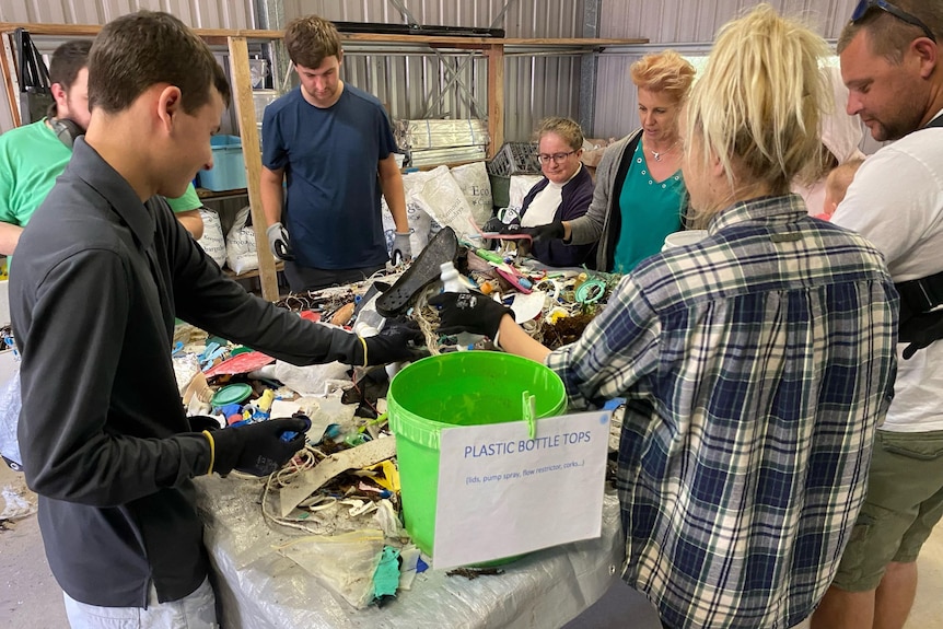Group of people sorting marine debris in a shed. 