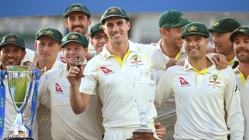 Pat Cummins holds the Ashes urn while standing in a group of his fellow players