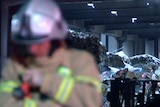 A fireman stands metres in front of a giant pile of plastic waste.