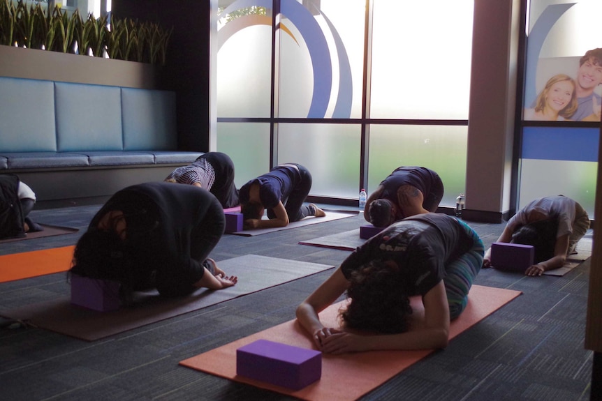 People in 'child's pose' in a yoga class.