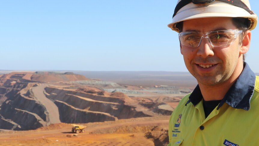 Man in the foreground left hand side in helmet and clear glasses, overlooking mine site below