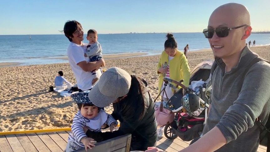 Four adults and two young children on the boardwalk at Melbourne's St Kilda beach.