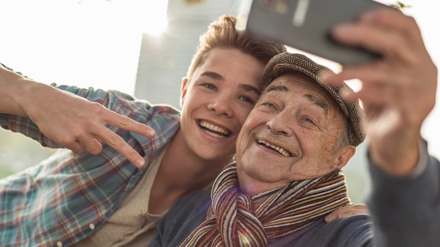 Grandson and grandpa using a smartphone, and laughing together.