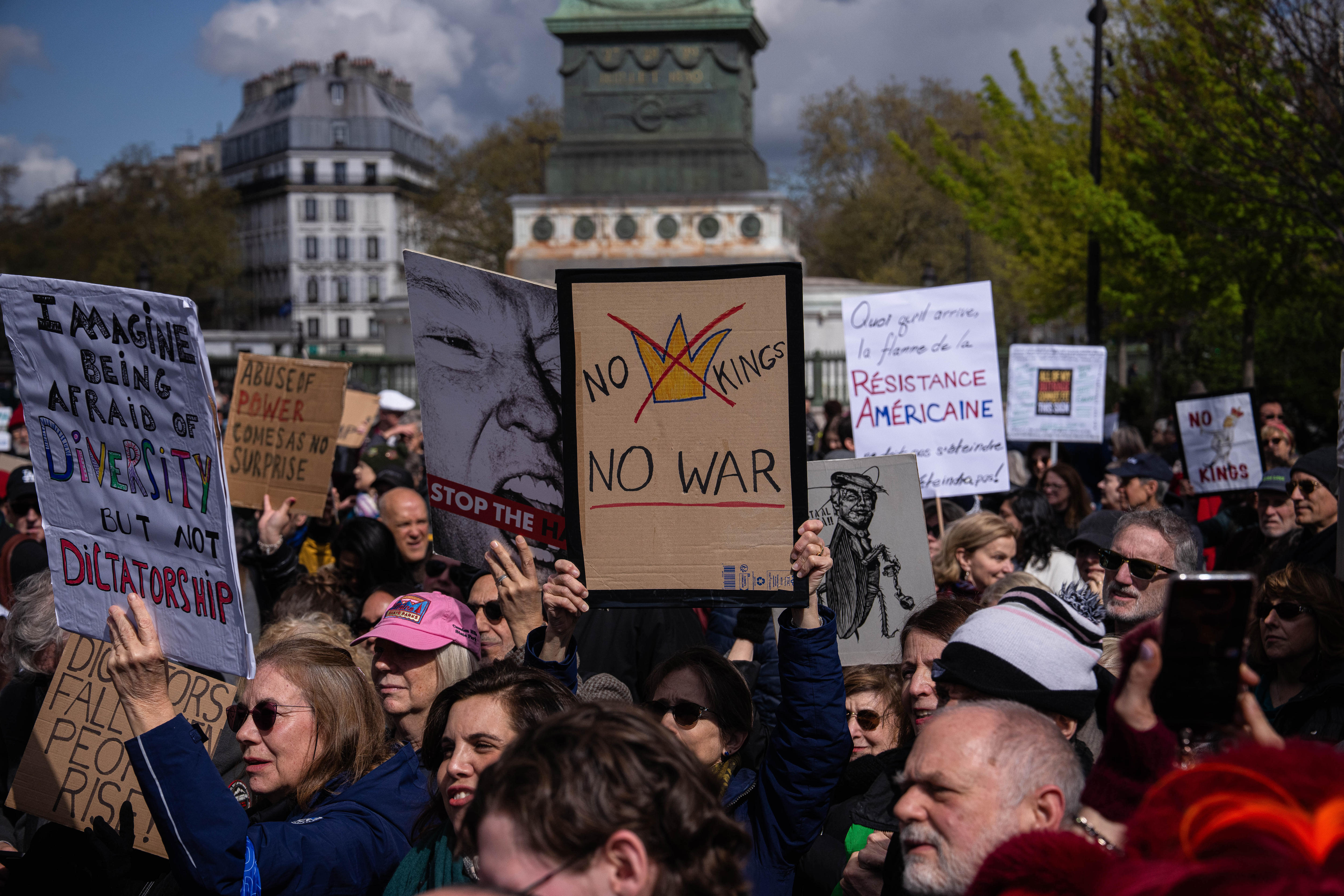 A woman holding a banner reading "No Kings, No War" takes part in the protest.