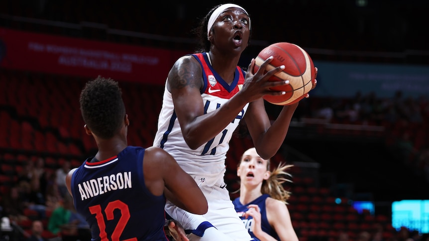 A USA player holds the ball in two hands as she drives to the basket at the Women's Basketball World Cup.