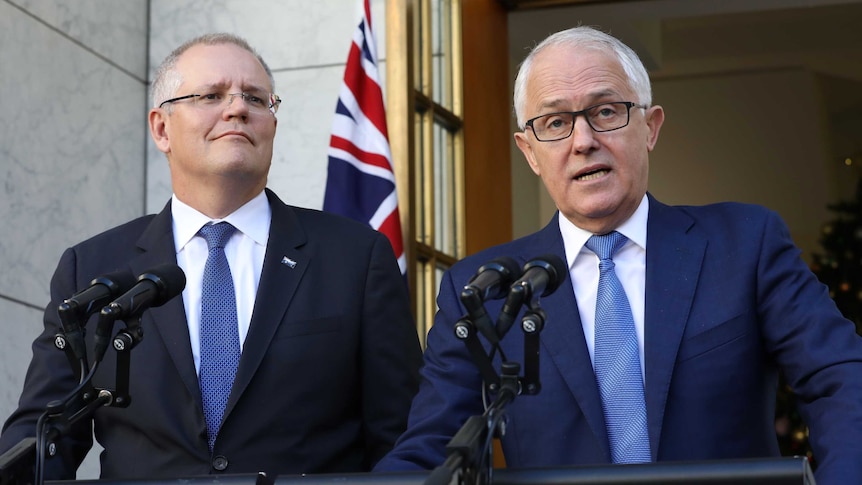 Scott Morrison and Malcolm Turnbull stand at two sets of microphones. Behind them is an Australian flag