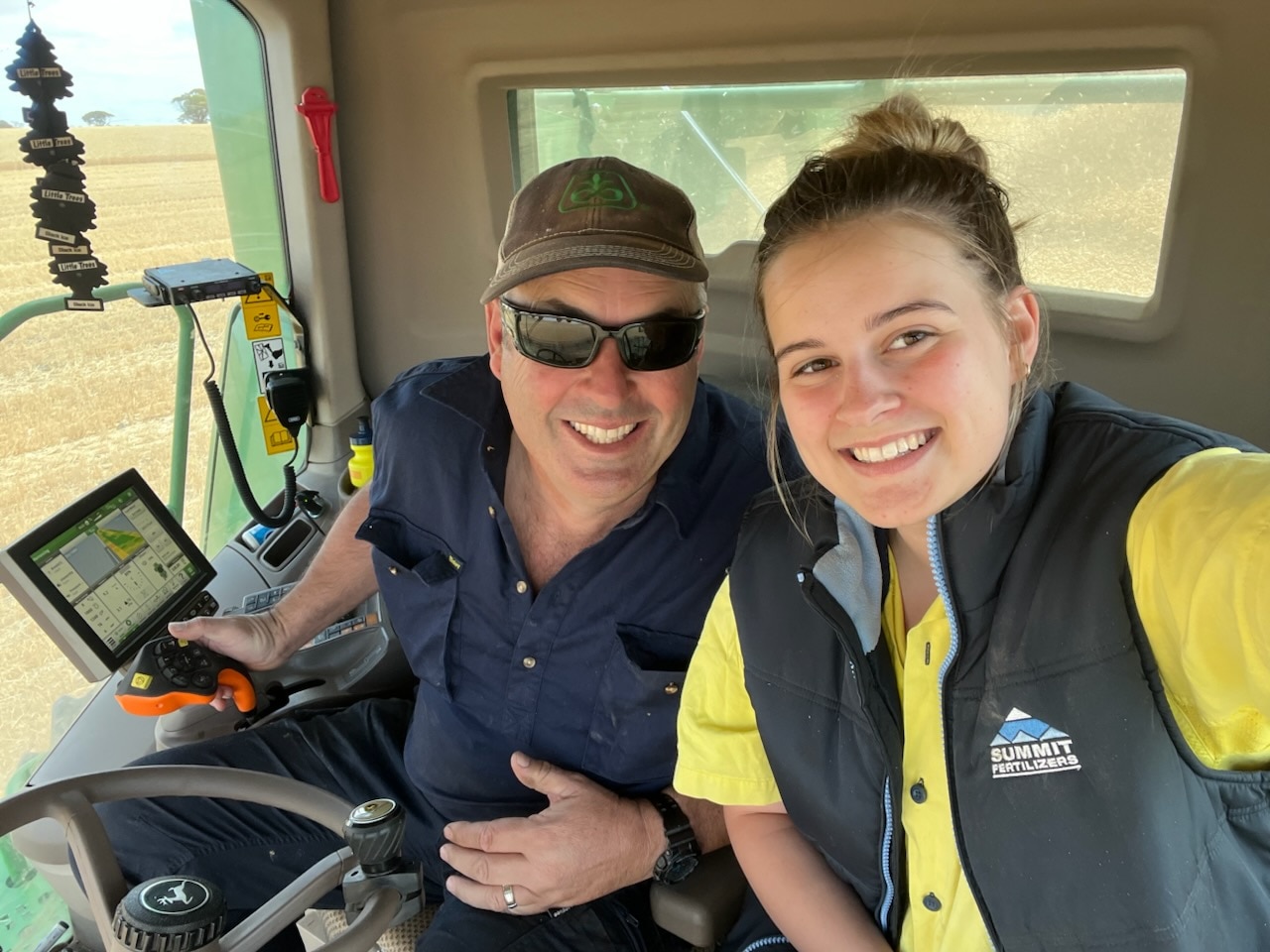 A couple in a harvester machine, smiling