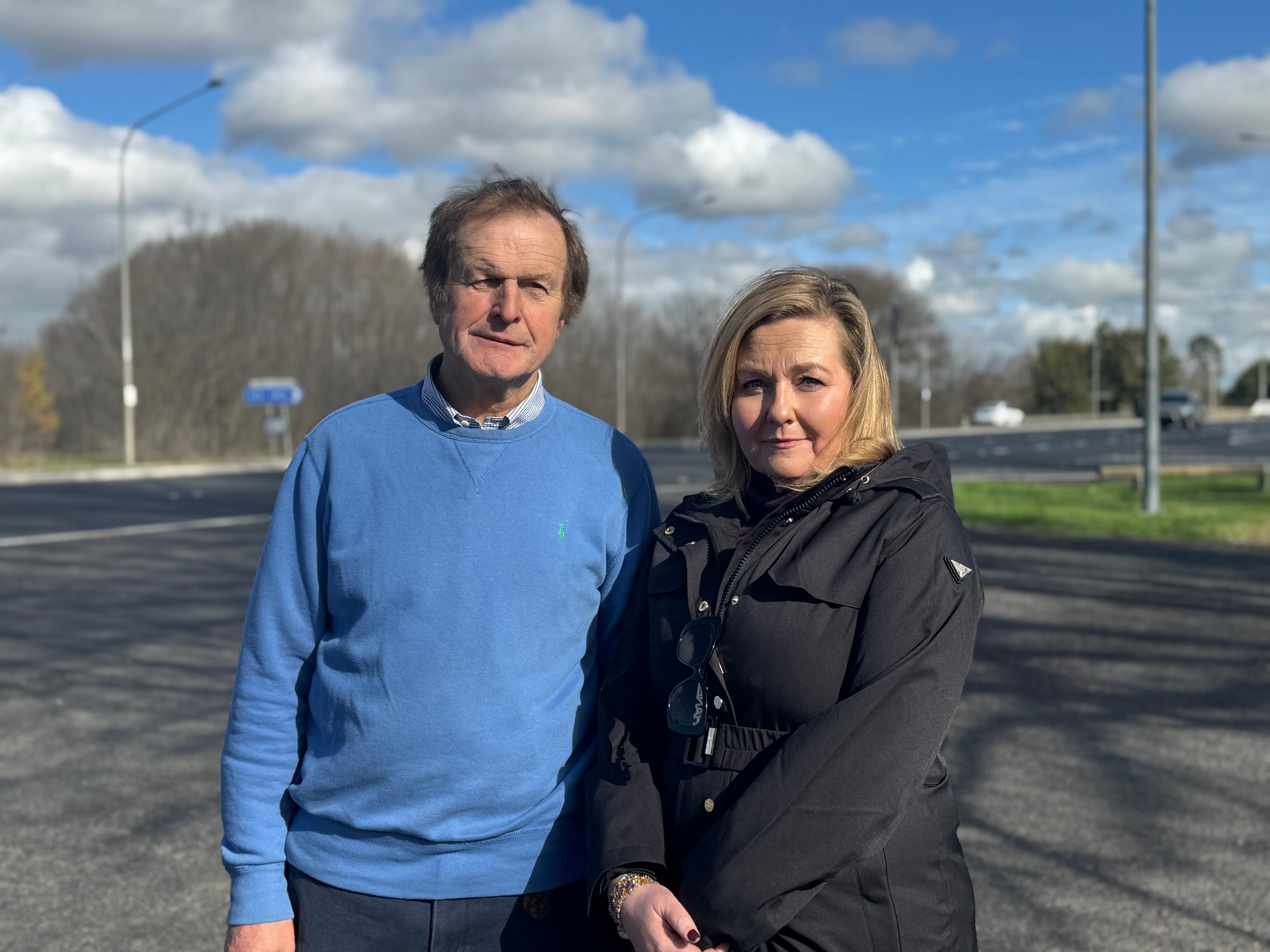 A man and woman stand in front of a highway.
