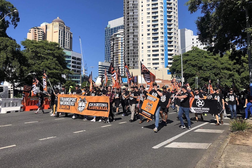 Transport Workers Union members march with banners in Brisbane's CBD on Queensland's Labour Day.