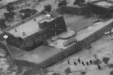 A black-and-white image from a video showing US forces advancing on the compound of IS leader Abu Bakr al-Baghdadi in Syria.