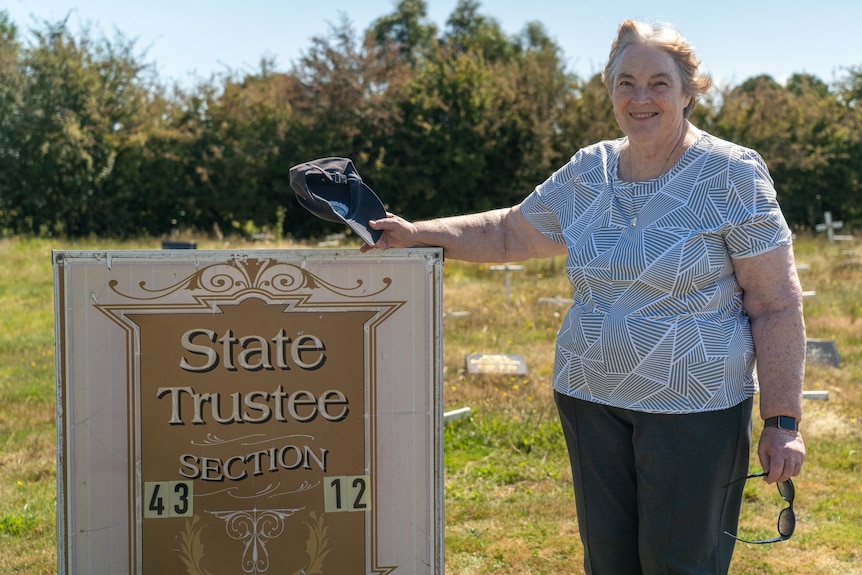 a woman stands next to a sign saying 'State Trustees Section'