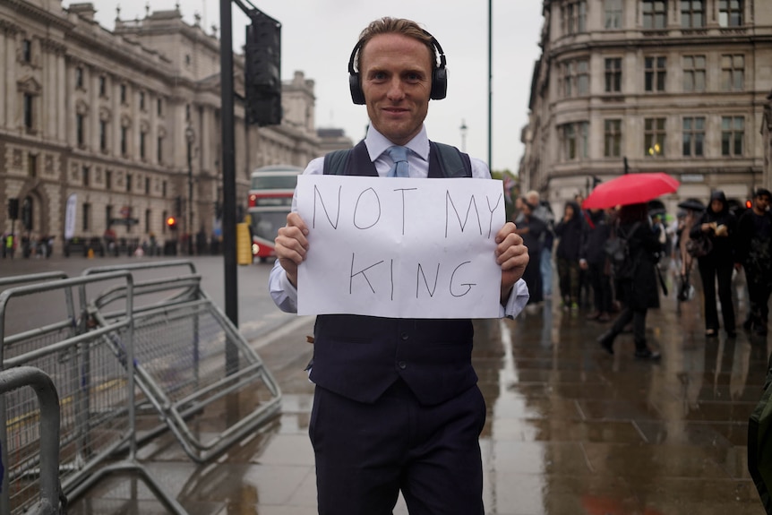 Paul stands with a not my king sign on a busy London footpath