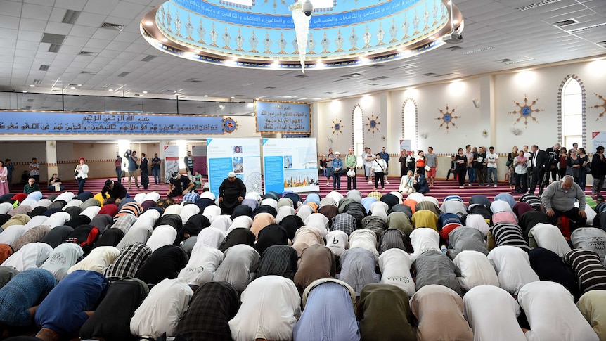Men kneel in prayer inside a mosque.