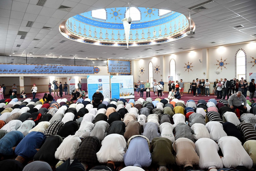 Men kneel in prayer inside a mosque.