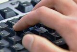 A close-up image of a hand typing on a black keyboard.