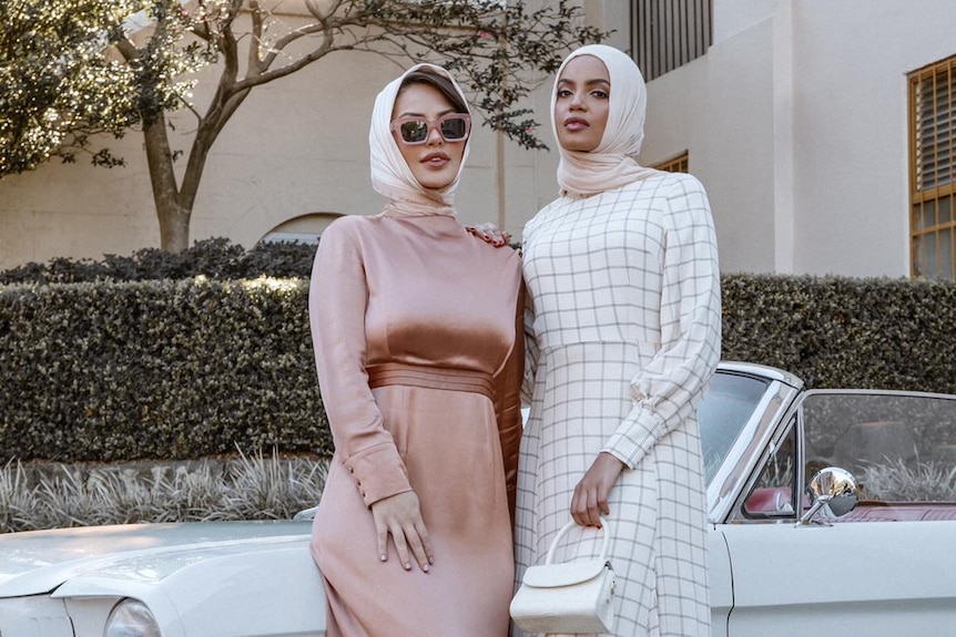 Two women posing in fashion dresses.